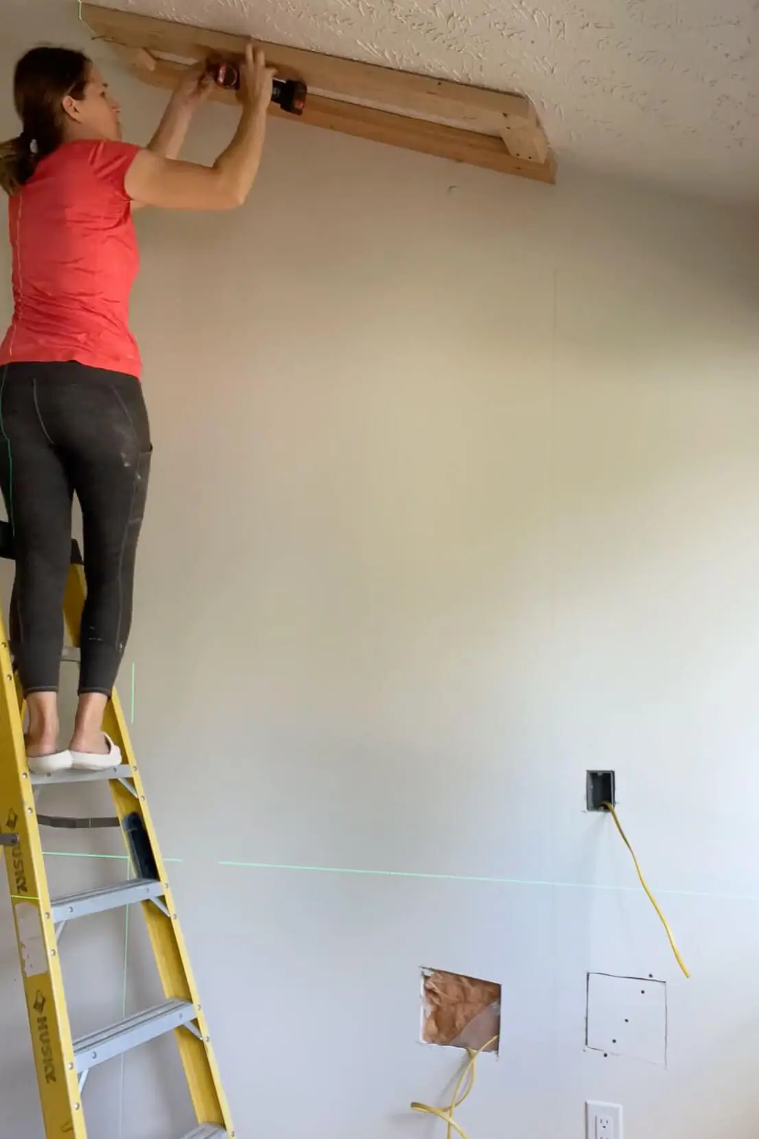 Attaching ceiling framing with a drill as part of the DIY fireplace wall structure.